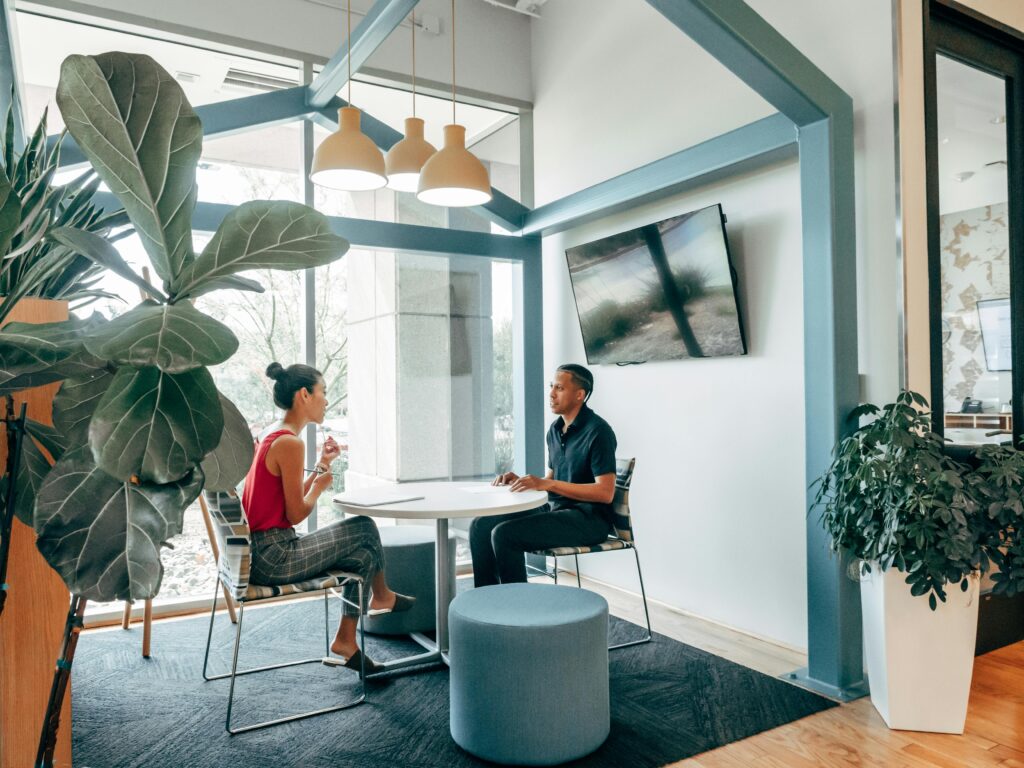 Zwei Personen sitzen in einem modernen Büro bei einem Gespräch an einem Tisch – symbolisches Bild für ein Vorstellungsgespräch, passend zum DaF-B1-PDF über Interviewfragen.