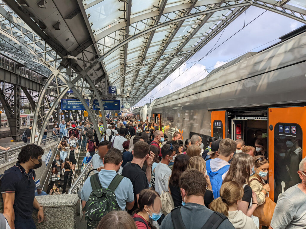 Viele Menschen stehen während der Stoßzeit auf einem Bahnsteig und steigen in einen Zug ein – öffentlicher Verkehr im Alltag