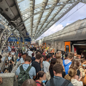 Viele Menschen stehen während der Stoßzeit auf einem Bahnsteig und steigen in einen Zug ein – öffentlicher Verkehr im Alltag